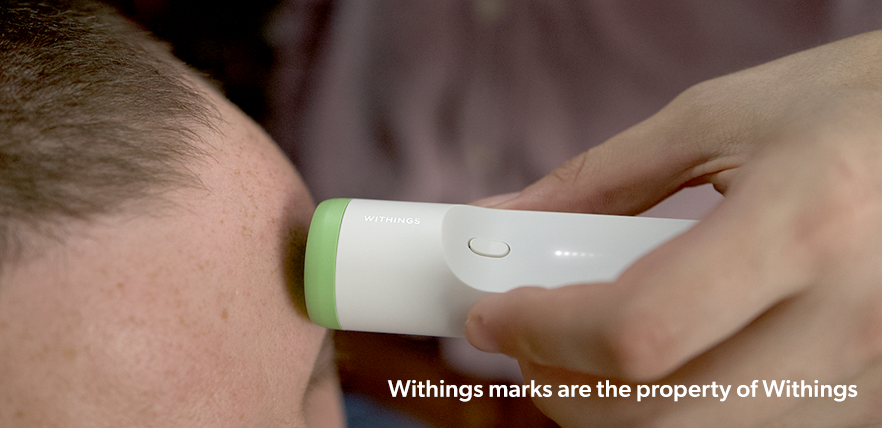 A person's temparature is being taken by using a Withings Thermometer